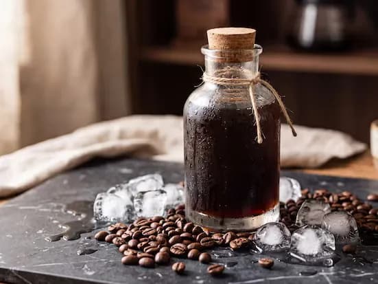 Liquid coffee extract in a corked glass bottle with ice and roasted beans
