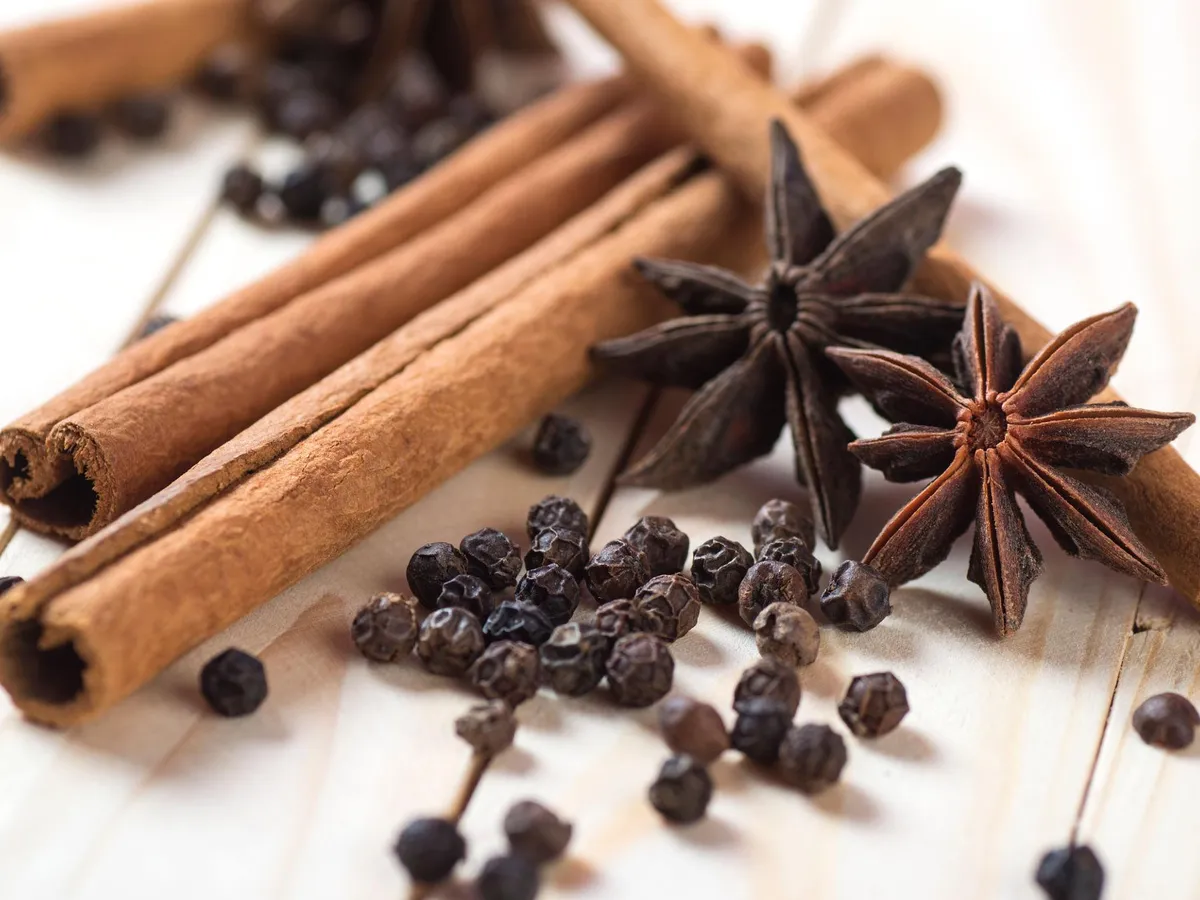 Cinnamon sticks, star anise and black peppercorns on light wood